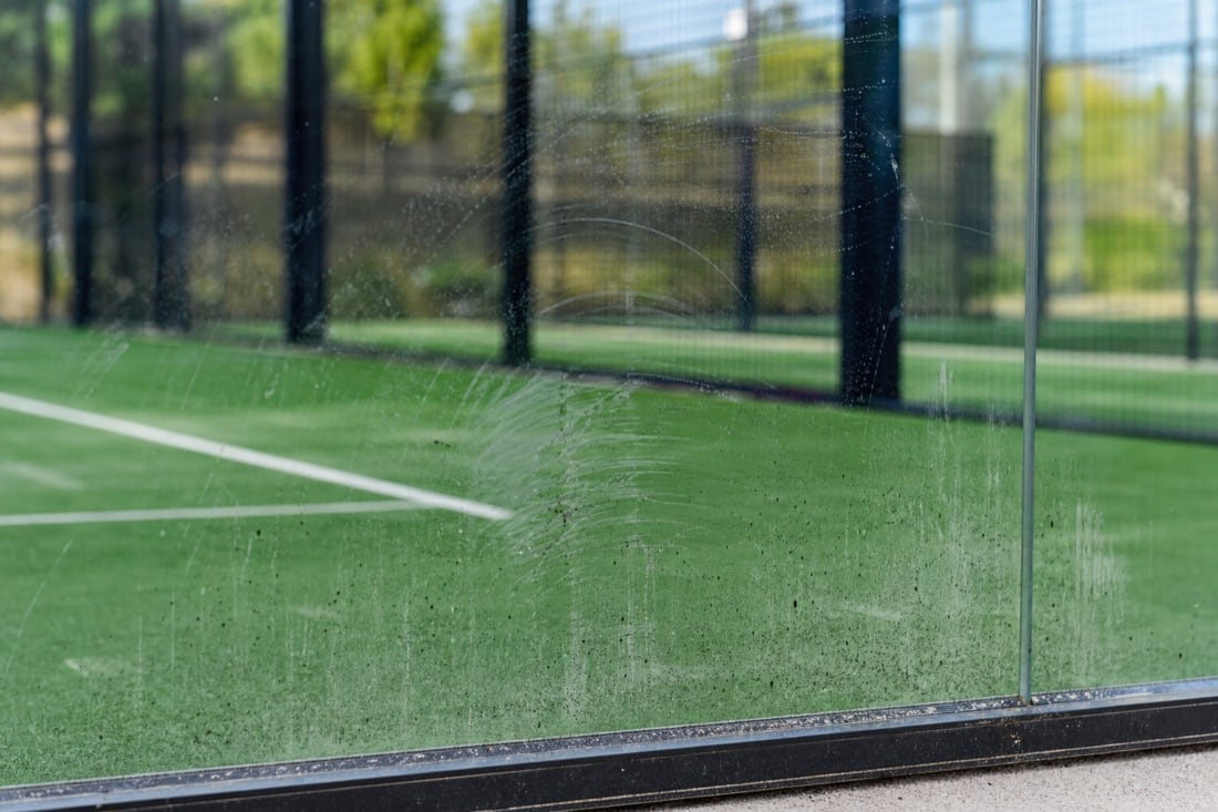 Rubberstrepen op padelglas als voorbeeld van zichtbare vervuiling